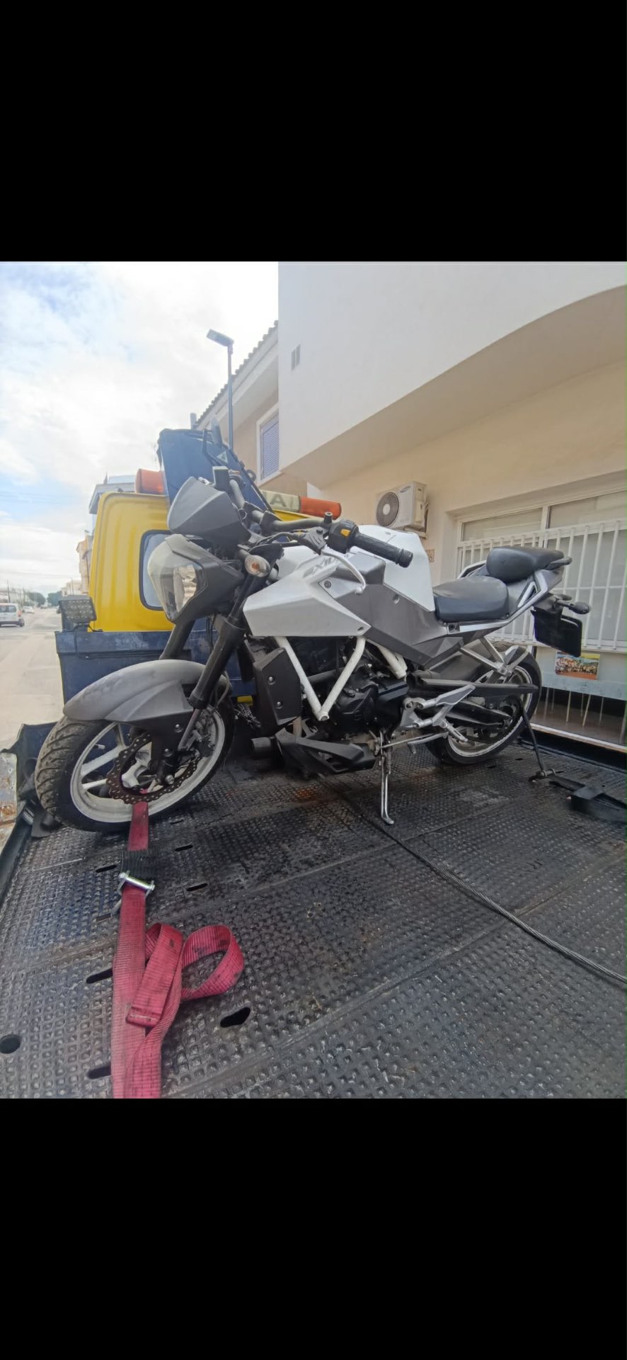 Furgoneta grúa con una motocicleta cargada para su recogida